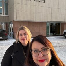 Tutkijat Jenny Paananen ja Kati Mäntysaari Turun yliopiston päärakennuksen edessä. Tutkijat hymyilevät. On talvi, ja taustalla näkyy lunta. Rakennuksen seinässä on teksti "Turun yliopisto. Vapaan kansan lahja vapaalle tieteelle".