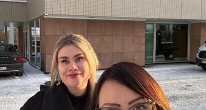 Tutkijat Jenny Paananen ja Kati Mäntysaari Turun yliopiston päärakennuksen edessä. Tutkijat hymyilevät. On talvi, ja taustalla näkyy lunta. Rakennuksen seinässä on teksti "Turun yliopisto. Vapaan kansan lahja vapaalle tieteelle".