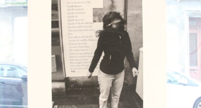 A photograph of a masked woman in front of a street poem.