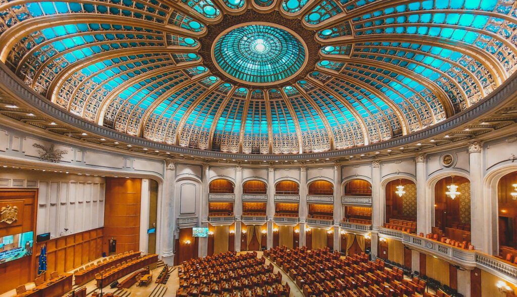 Vibrant interior of a parliament hall with a grand dome and intricate architecture.