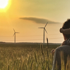 Aikuinen ja lapsi katselevat tuulivoimaloita pellolla
