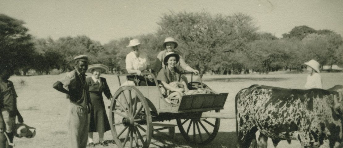 vanha valokuva, jossa eurooppalaisia härkävankkureiden kyydissä ja afrikkalaisia vieressä