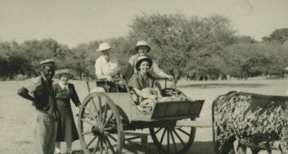 vanha valokuva, jossa europpalaiset naiset istuvat härkävankkureilla, viereissä afrikkalaisia
