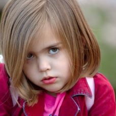 Tyttö joka katsoo kameraan alta kulmien.