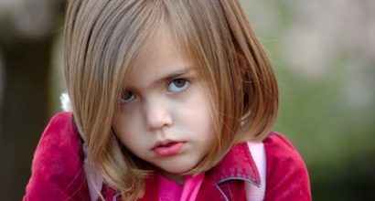 Tyttö joka katsoo kameraan alta kulmien.