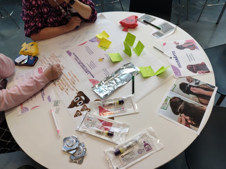 Kuva ideapitserian pöydästä, jossa on muun muassa muistilappuja, kuvia, tarroja ja näytteenottovälineitä.