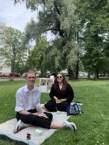 Kaksi ihmistä piknikillä Kupittaanpuistossa lukemassa kirjoja ja syömässä jäätelöä