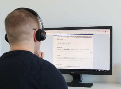 Henkilö tietokoneen ruudun edessä kuulokkeet korvilla suorittamassa puheen sujuvuusarviointia