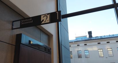 Näkymä Varsinais-Suomen käräjäoikeudesta, jossa salin oven yläpuolella kuulosilmukka-merkki.
