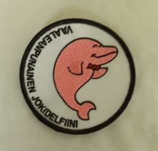 Haalarimerkki, jossa on vaaleanpunainen jokidelfiini.