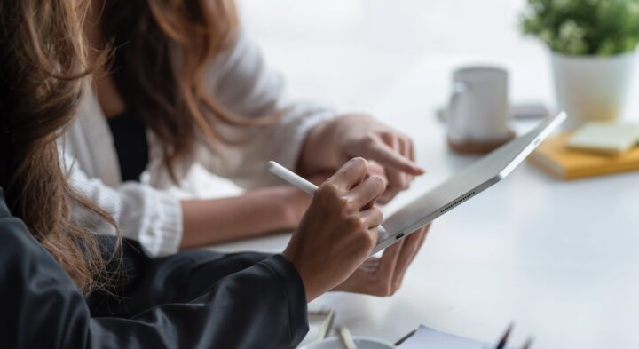 Kädet osoittaa tablettia.