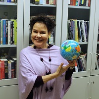 A smiling woman holds a globe toy and looks straight ahead.