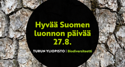 Hyvää Suomen luonnon päivää -teksti. Puunrunko taustalla.