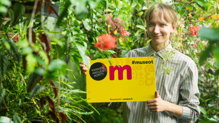 jättikokoinen Museokortti nuoren miehen kanssa kasvien keskellä puutarhassa.
