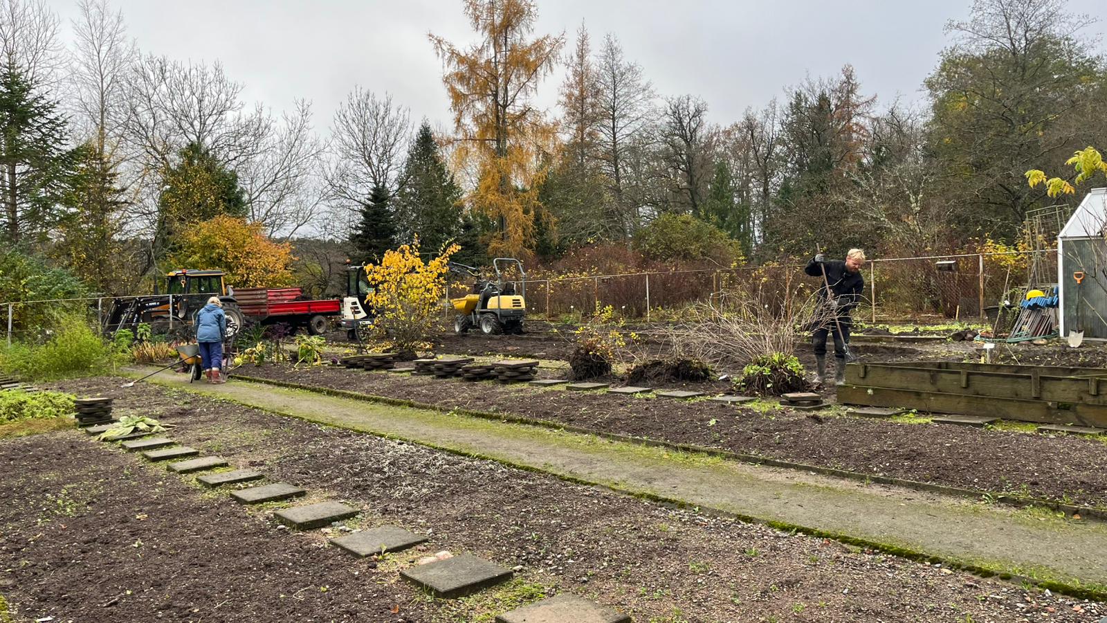 Ihmisiä töissä talousmaalla syksyllä kun kasvit ovat jo poissa. 