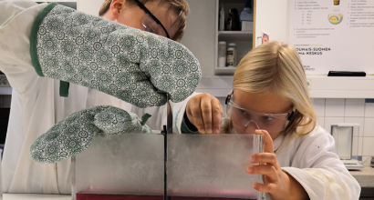 kaksi lasta laboratoriossa puuhaamassa