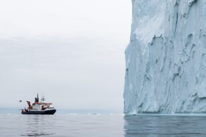 Tutkimusalus tyynellä merellä valtavan jäävuoren vieressä