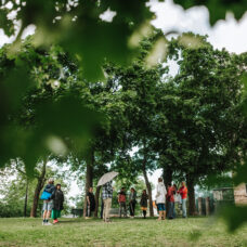 People standing under decidious trees in an urban park next to the Turku art museum. It is summer.