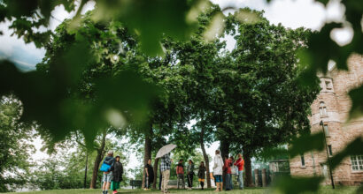 People standing under decidious trees in an urban park next to the Turku art museum. It is summer.