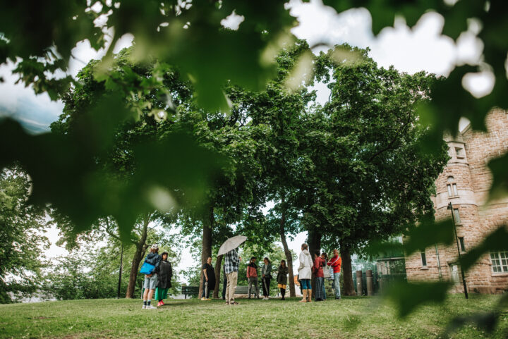 People standing under decidious trees in an urban park next to the Turku art museum. It is summer.