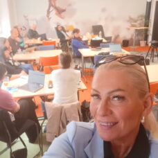 Naisselfie taustalla osallistujia luokkahuoneessa