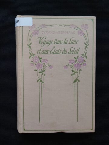 The cover of the book covered with cream colored cloth. At the top the title and authors name are framed with pink and green flower motive.