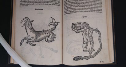 The picture shows the opening of a book. On both pages the text is printed at the top of the page and at the bottom are pictures of constellations. On the left-hand page, the constellation of capricornus is shown. The picture shows an animal with a goat's front body and a snake-like tail. On the right is an aquarius. The naked male figure is kneeling, carrying a large pot from which water is flowing down past him.