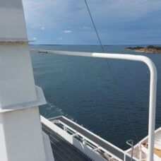 Kuva aurinkoiseen aavaan saaristoon laivan takakannelta osan valkoisista rakenteista näkyessä kuvassa