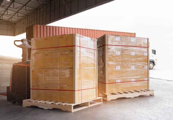 Cargo shipment loading for truck. Freight truck for delivery service. Warehouse dock load pallet goods into container truck. Stacked boxes wrapped plastic on pallet rack.