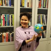 Photo of Benita Heiskanen smiling while holding a globe, against the backdrop of a bookshelf. Links to her profile at the University of Turku website.