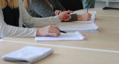 Ihmisiä kirjoittamassa paperille muistiinpanoja