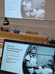 Blanka Henrikson näyttää luennolle osallistujille kuvan, jossa on esimerkki keittiöiden sisustuksen kehittämisestä tieteellisin menetelmin. Sama kuva näkyy tietokoneen näytöllä.