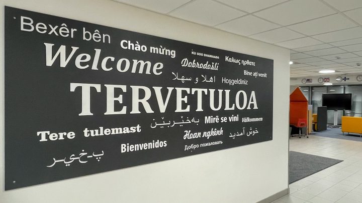 Alakoulun aulassa oleva taulu, jossa Tervetuloa-teksti usealla kielellä