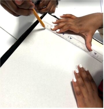 Kädet mittaamassa ja piirtämässä paperille
