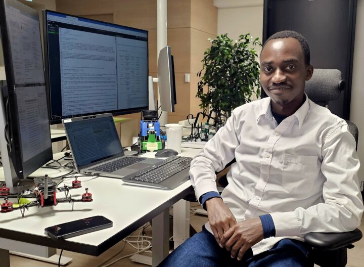 Amos Alwala sitting at a desk by a computer