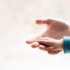 Lapsen käsi aikuisen kädessä.